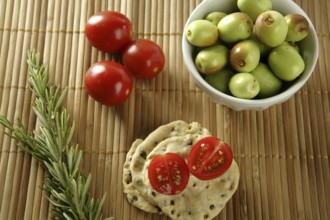 Sesame seeds biscuits over bamboo stripes, tomatoes ans rosemery