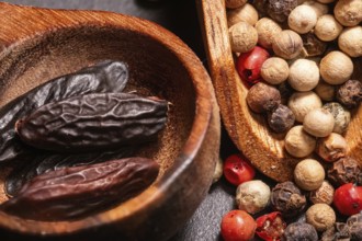 Tonka Beans and different kind of Peppercorns in a wooden spoon