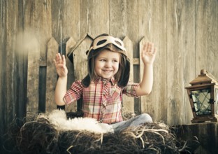 Happy kid playing in pilot helmet near the wooden background