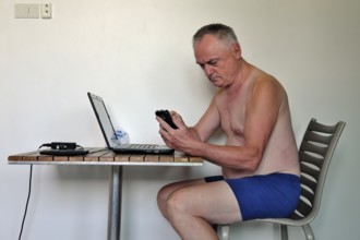 Businessman, freelancer, 60 plus on holiday working with laptop and mobile phone, Pattaya,