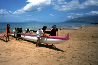 Kihei beach, an outrigger boat is pushed ashore by schoolgirls after physical education class, Maui
