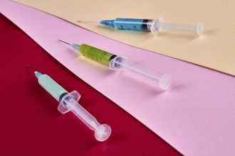 Close-up three syringes filled with multicolored medicine liquids. Drugs addiction and injections