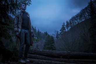 Young man in the forest at night. Early morning