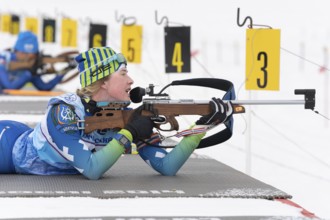 Sportswoman biathlete Legostaeva Anastasia rifle shooting in prone position. Biathlete in shooting
