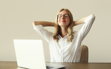 Relaxed happy young woman take a break meditates working with laptop sitting at desk in office or