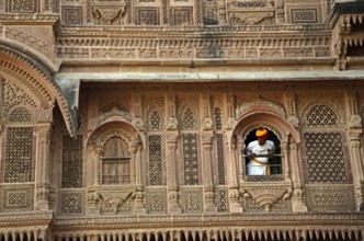 Man peeping out of palace window at Mehrangarh Fort, Jodhpur, Rajasthan, India, Asia