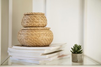 Close-up of a round straw box with a lid on a white shelf. Eco-friendly items for storing small