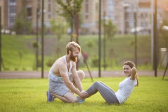 Sit ups fitness couple exercising sit up outside in graß Fit people working out cross training.