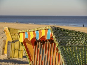 Close-up of a colourful beach chair on a sandy beach, overlooking the calm sea under a clear blue