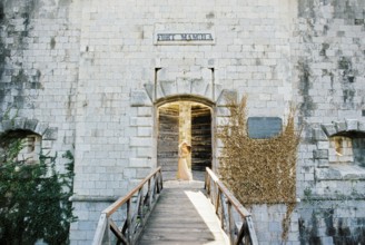 Groom hugging bride behind the half-opened door of Mamula Fort.