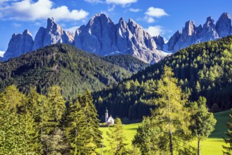 Dolomites, Tirol. Sunny warm autumn day. Rocky peaks and forested mountains surrounded by green