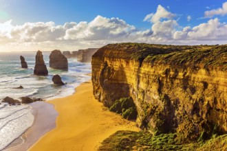 Rocks of the Twelve Apostles at sunset. Powerful Pacific surf breaks down on the shore. Grandiose