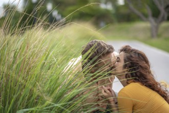 Couple secretly kissing behind a bush in a park