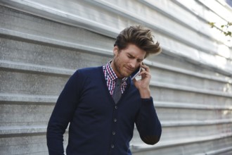 Young businessman talking smartphone phone on the street metal fence