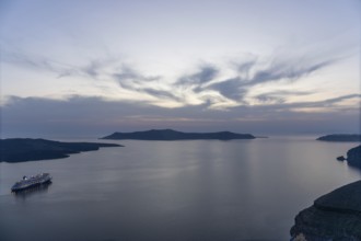 Evening atmosphere after sunset over the island of Thirassia, cruise ship in the archipelago of