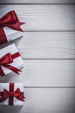 Present boxes with red bows on wooden board holidays concept