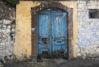 Entrance of an abandoned house with a blue damaged wooden door from a traditional house in Cyprus