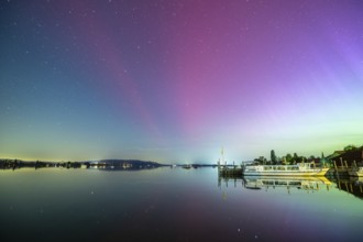 Calmness of the lake at night with starry sky, northern lights and a boat in the background,
