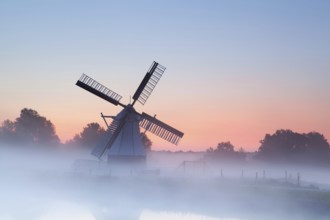 Charming Dutch windmill in morning sunrise fog, Groningen, Netherlands