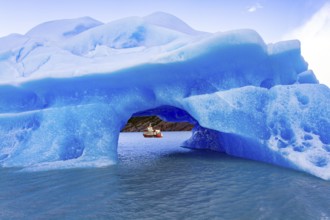 Huge iceberg has broken off from the Gray Glacier and drifts across the lake. Boat with tourists