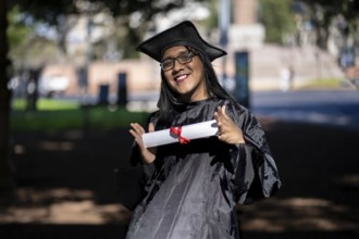 Latin transgender woman recent graduated, dressed in cap and gown, showing off his degree