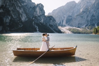 Bride and groom sailing in wooden boat, with oars at Lago di Braies lake in Italy. Wedding in
