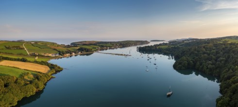 An aerial panorama landscape in warm evening light over Castlehaven Bay with many sailboats