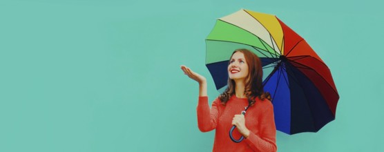 Autumn portrait of happy smiling young woman holding colorful umbrella wearing red knitted sweater