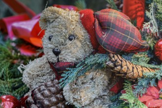 Close up of a Christmas decoration with red Christmas baubles, red candles, a green fir tree and a