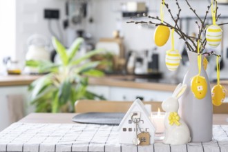 Key to house of cozy home with Easter decor with rabbit and eggs on table of kitchen. Building,