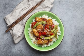 Asian sweet and sour sticky chicken with vegetables stir-fry and rice in ceramic bowl with