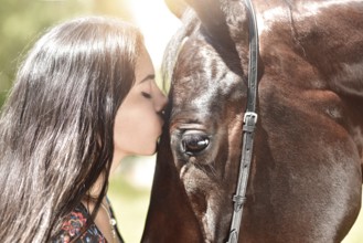 Horse and girl share an emotional moment in close up shot as they appear to kiss