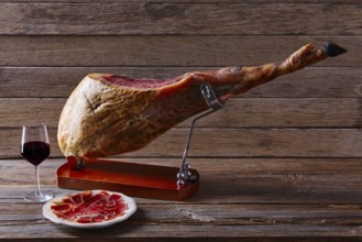 Iberian ham pata negra from Spain with red wine on wood background