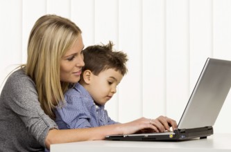 Mother and son at the computer, symbol of working from home, family and career, double burden