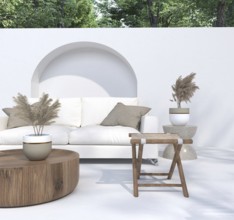 Outdoor seating area with a white sofa, potted plants, and wooden table under bright light