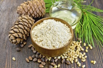 Flour cedar in a wooden bowl, cedar nuts and two cones, the oil in the glass carafe, cedar branch