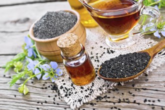 Nigella sativa oil in vial, gravy boat and bottle, seeds in a spoon and black cumin flour in a bowl