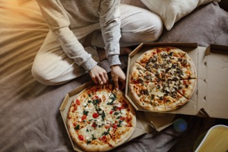 Person in pajamas enjoying pizza in bed