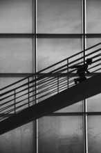 The silhouette of a boy climbing a staircase in a stooped posture