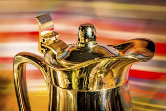 Shiny coffee pot against a colourful background