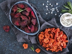 Baked beet and carrot slices with coarse sea salt scented rosemary. Vegan diet food idea and recipe