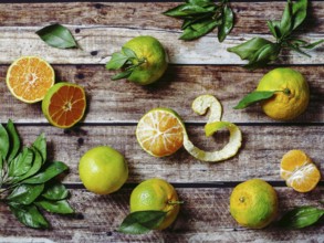 Green mandarines on old wooden background. Fresh ripe half, whole and peeled green tangerines with