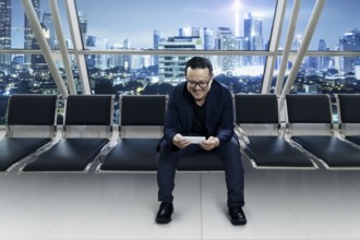 Young smiling businessman sitting at conference room and using smart phone