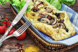 Baking with dough with meat and mushrooms in glass form and kitchen fork and knife