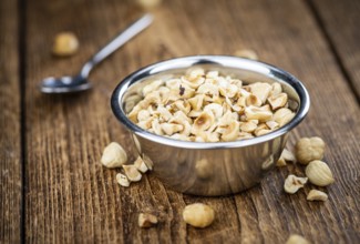 Portion of freshly chopped Hazelnuts on an old wooden table as detailed close up shot (selective