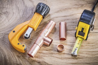 Copper water pipe cutter connectors tape measure on wood board plumbing brassware concept