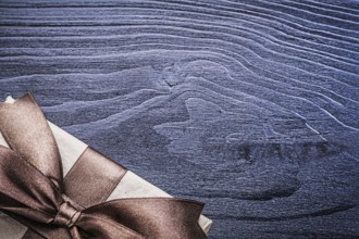 Present box with satin bow on wooden board