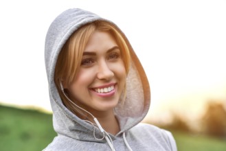 Beautiful young woman with headphones glad after nice jogging in city park