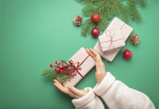 Christmas or New Year celebration green paper festive background with female hands holding wrapped
