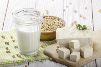 Non-dairy alternatives Soy milk or yogurt in mason jar and tofu on white wooden table with soybeans